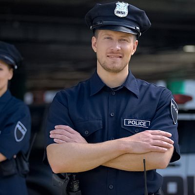 Ein Polizist in Uniform mit verschränkten Armen und freundlichem Gesicht
