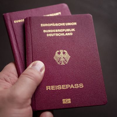 Hand hält zwei rote Reisepässe der Bundesrepublik Deutschland in der Hand