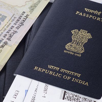 Nahaufnahme eines indischen Reisepasses mit goldenen Verzierungen, in dem mehrere Flugtickets stecken